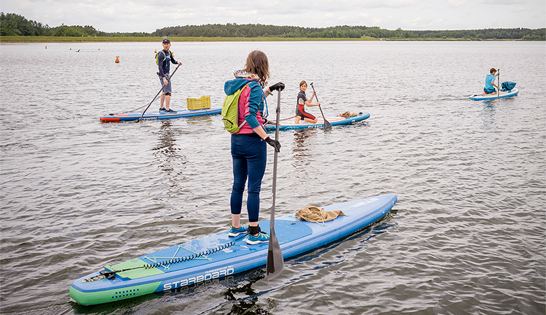 Mehrere Jugendliche auf Stand-up-Boards auf dem Wasser.