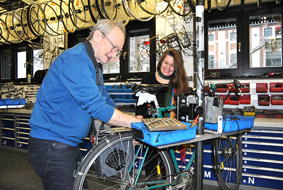 Zwei Personen reparieren ein Fahrrad in einer Werkstatt.