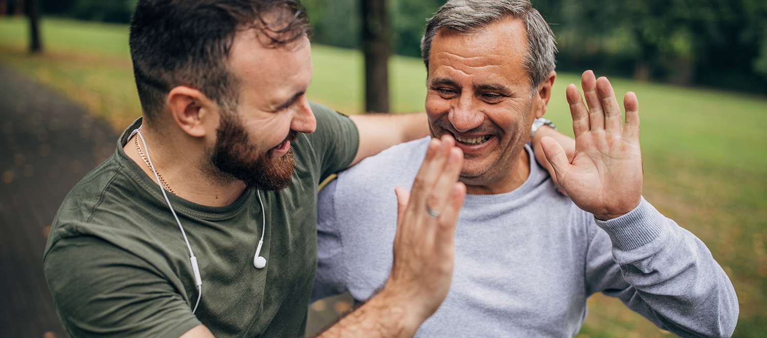 Zwei Männer beim Joggen im Park geben sich ein High five