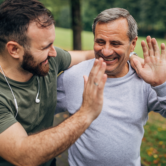 Zwei Männer beim Joggen im Park geben sich ein High five