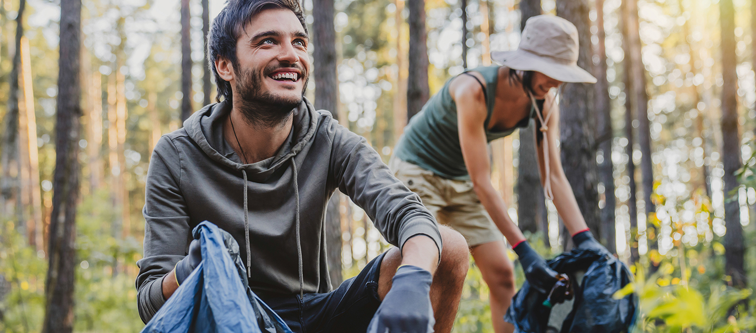 Zwei Personen beim Müllsammeln im Wald 