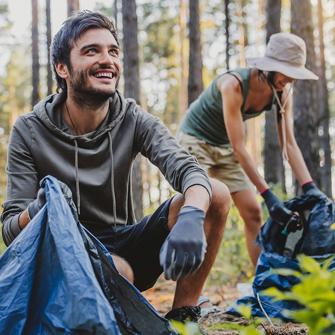 Zwei Personen beim Müllsammeln im Wald.