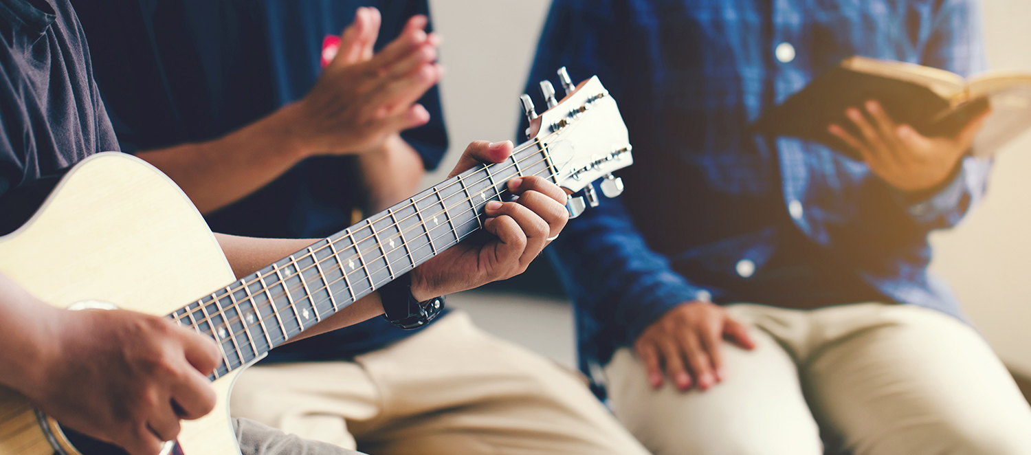 Drei Personen sitzen zusammen und machen gemeinsam Musik