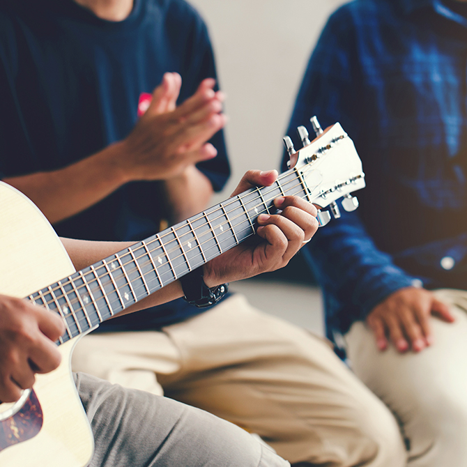 Eine Person spielt für andere Personen Gitarre