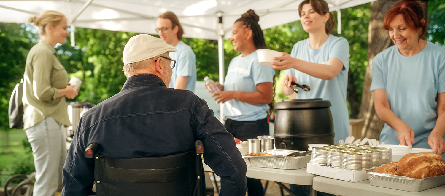 Ein Mann im Rollstuhl nimmt Essen an einer Ausgabe von Freiwilligen entgegen.