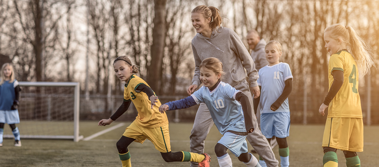 Eine Fußball-Trainerin und ihre Mädchenmannschaft auf dem Fußballplatz.